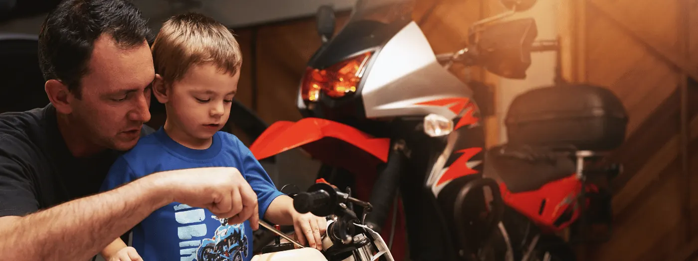 A father and son working on a dirt bike in the garage