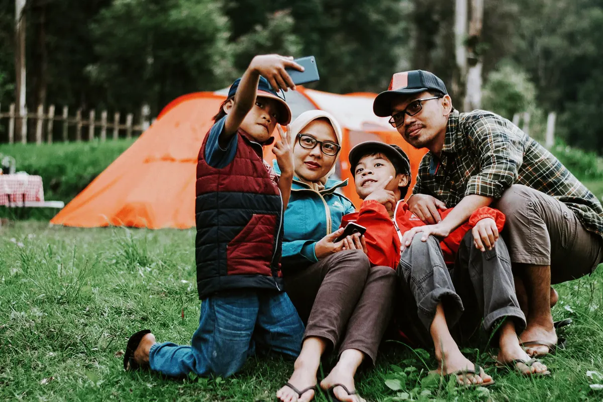 A family sitting together outside a tent at a bush campsite