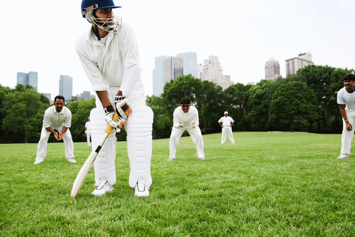 A junior cricketer batting on a suburban ground with fielders behind