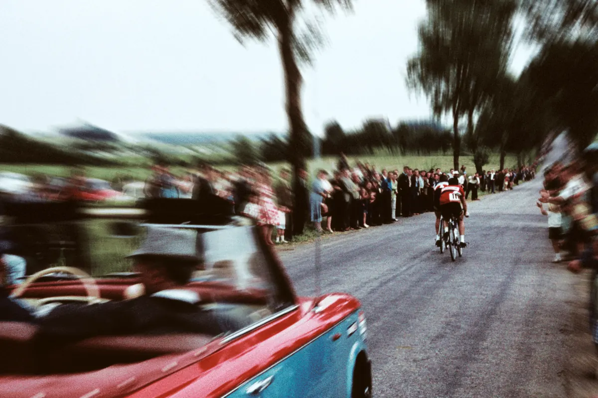 A classic convertible blurring past a line of palm trees