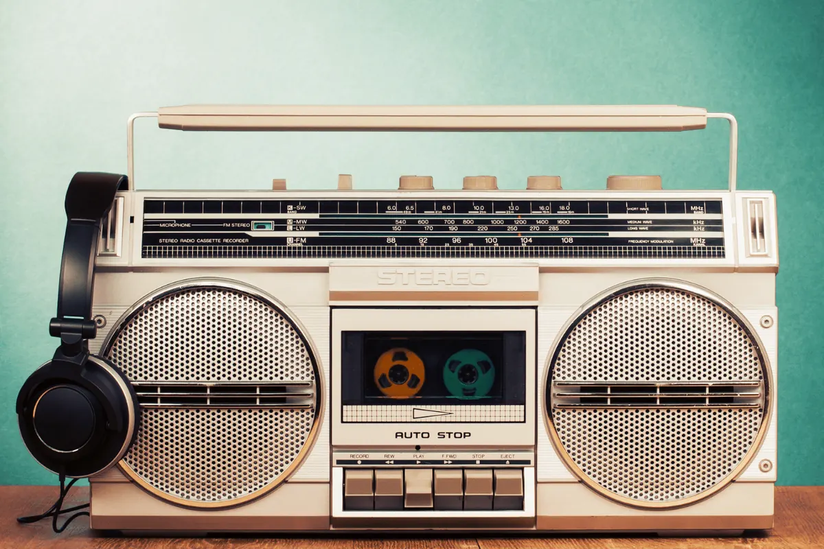 A twin-cassette boombox with headphones resting against it