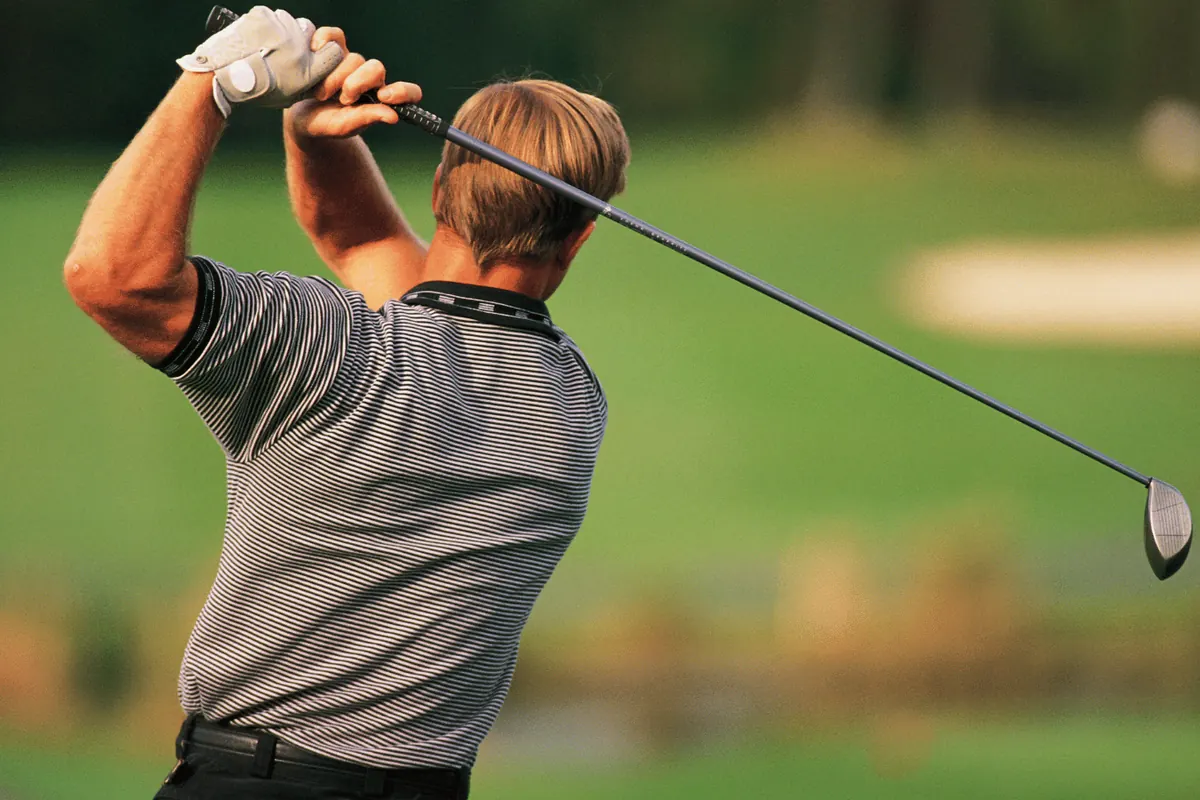 A golfer at the top of his follow-through on the fairway