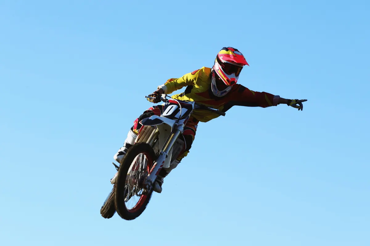 A motocross rider mid-jump against a clear sky