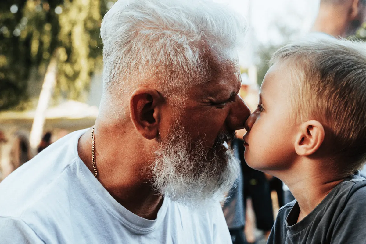 A grandson kissing his grandfather on the cheek