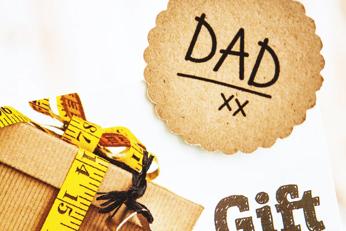 A gift card and a tag reading Dad beside a retractable tape measure
