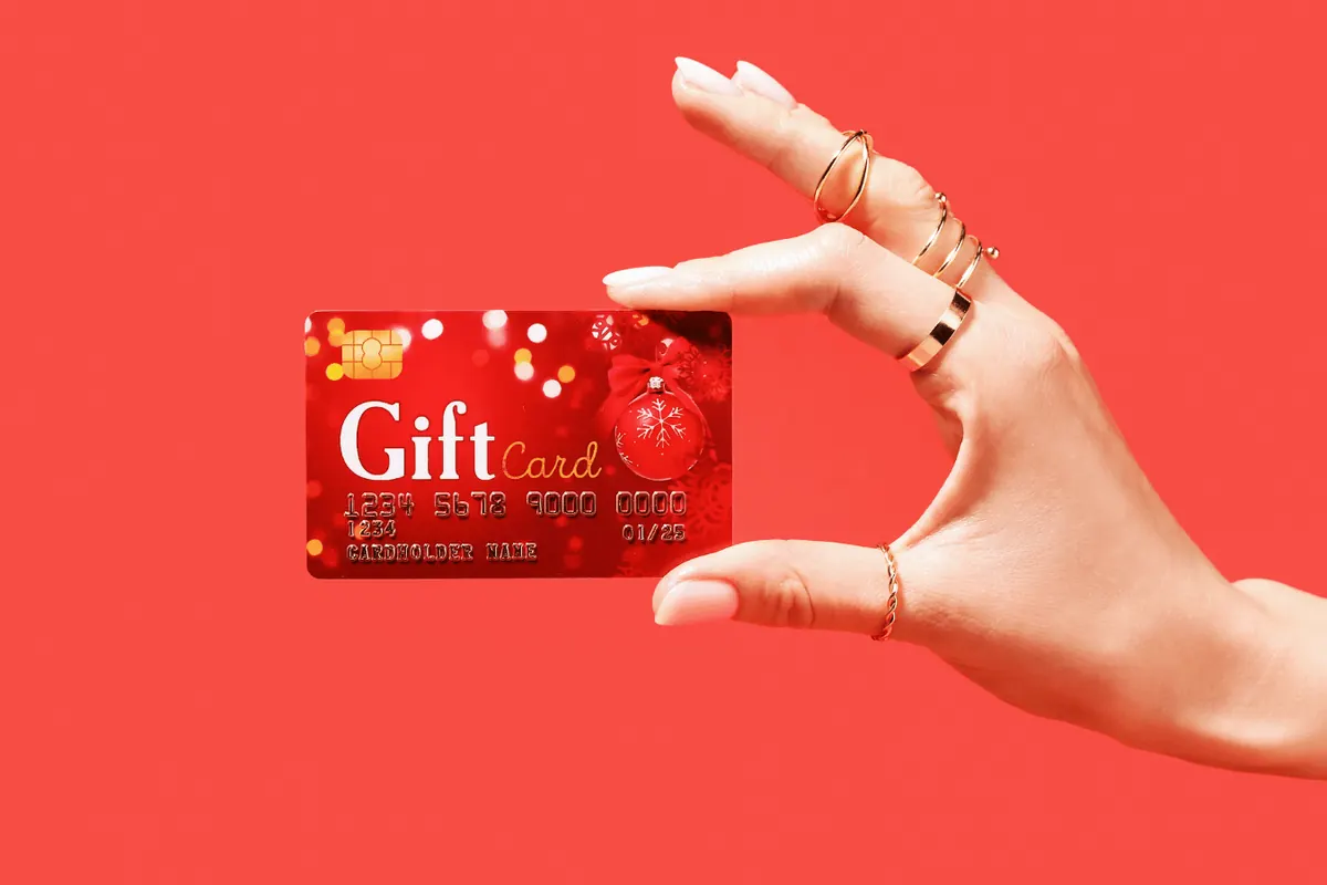 A hand holding out a red gift card against a red background