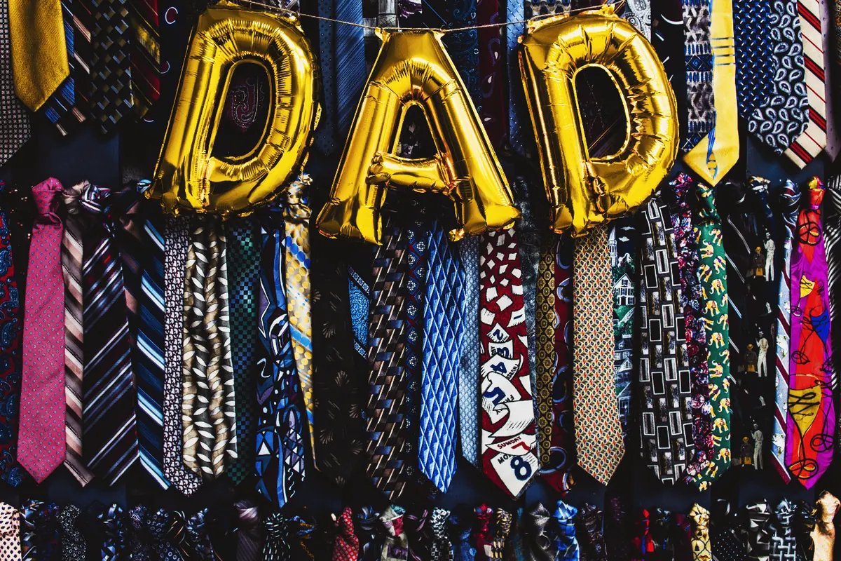 Gold DAD balloons strung above a rack of patterned ties