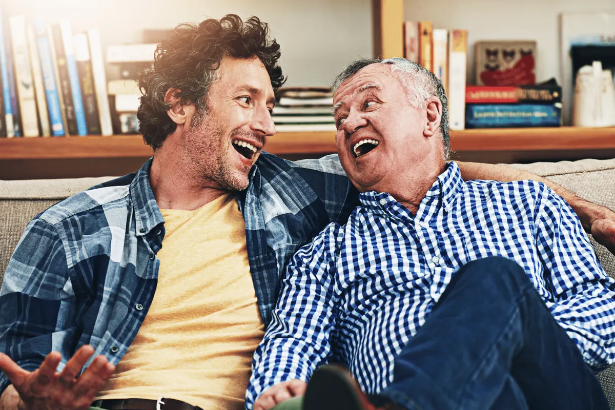 Two men sitting on the floor of a lounge room laughing together