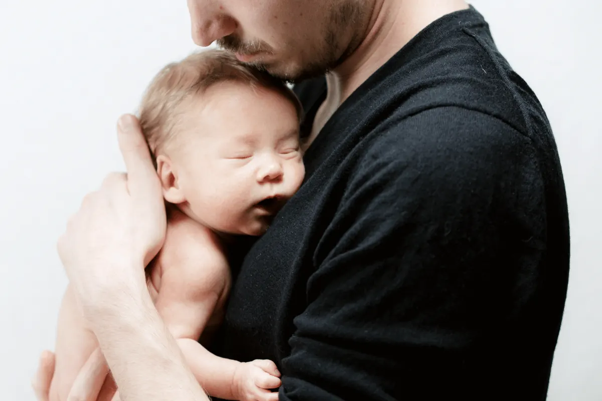 A newborn asleep against his father’s chest